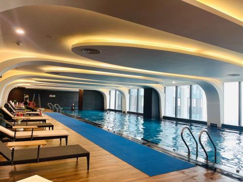 a large swimming pool in a hotel with tables and chairs at 2 Bedroom Luxury Apartment Diamond Crown Hai Phong in Ðông Khê