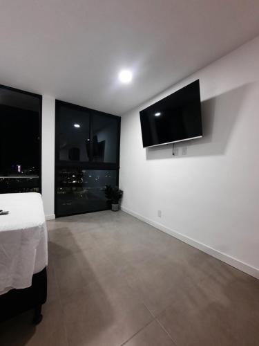 a white room with a bed and a flat screen tv at Nuevo y moderno loft en Bö Escalante in San José