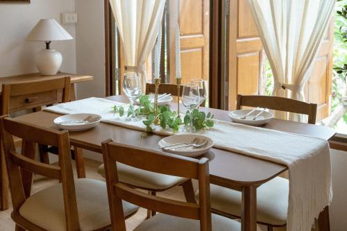 a dining room table with chairs and a wooden table with wine glasses at Gemstone Riverside, Chanthaburi in Chanthaburi
