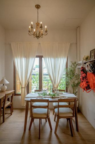a dining room with a table and chairs and a chandelier at Gemstone Riverside, Chanthaburi in Chanthaburi
