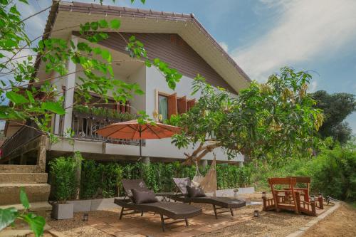 a house with a patio with chairs and an umbrella at Gemstone Riverside, Chanthaburi in Chanthaburi