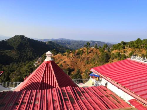 a red roof on a building with a mountain in the background at Little Chilli Studios in Shimla