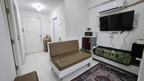 a living room with a couch and a flat screen tv at Apartemen 2BR dekat Jakabaring Sport Center & Opi Mall in Baguskuning