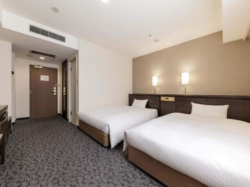 a hotel room with two beds and a television at Nishitetsu Inn Kokura in Kitakyushu