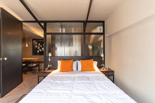 a bedroom with a large bed with two orange pillows at Thip Residence at Surawong in Bang Rak