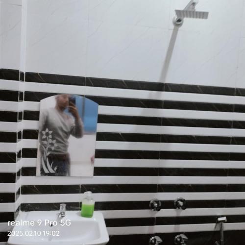 un hombre tomando una foto en un espejo en un baño en Kishan guest house, en Ayodhya