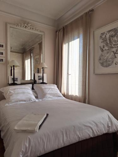 une chambre avec un grand lit blanc avec un miroir dans l'établissement Plein Centre Charmant et Lumineux, à Paris