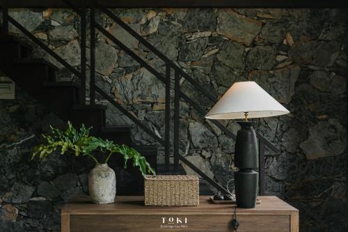 a lamp on a table with a stone wall at TOKI Ecolodge Cao Răm in Hòa Bình
