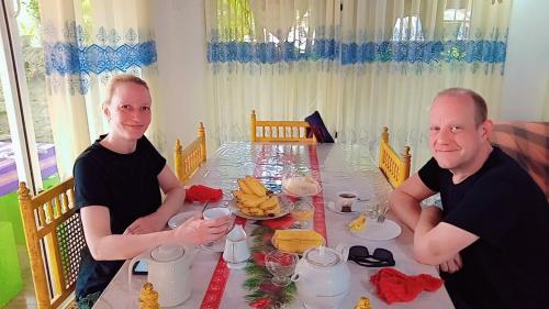 two men sitting at a table with food on it at Green Garden Homestay in Giritale