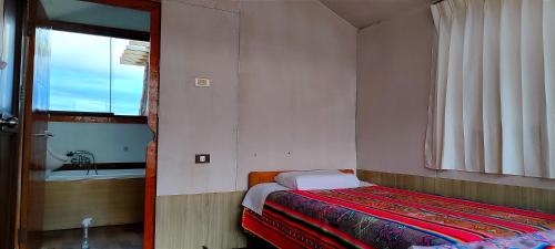 een kleine slaapkamer met een bed en een wastafel bij Lago Titicaca in Puno