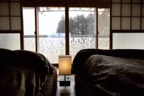 a bedroom with two beds and a large window at 期間限定連泊割-新幹線徒歩15分-空港車8分-田んぼに囲まれて暮らす自然に寄り添う静かな一棟貸切宿 in Hanamaki