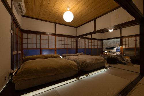 a room with two beds in a room with windows at 期間限定連泊割-新幹線徒歩15分-空港車8分-田んぼに囲まれて暮らす自然に寄り添う静かな一棟貸切宿 in Hanamaki