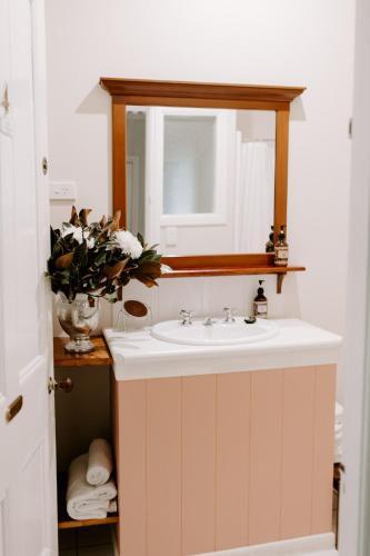 a bathroom sink with a mirror and a vase of flowers at The Abbey in Warwick