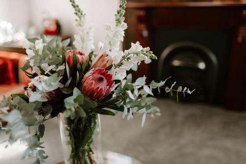 a vase filled with red and white flowers on a table at The Abbey in Warwick