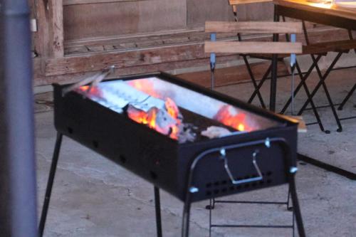 a grill with a fire in it next to a table at 期間限定連泊割-新幹線徒歩15分-空港車8分-田んぼに囲まれて暮らす自然に寄り添う静かな一棟貸切宿 in Hanamaki