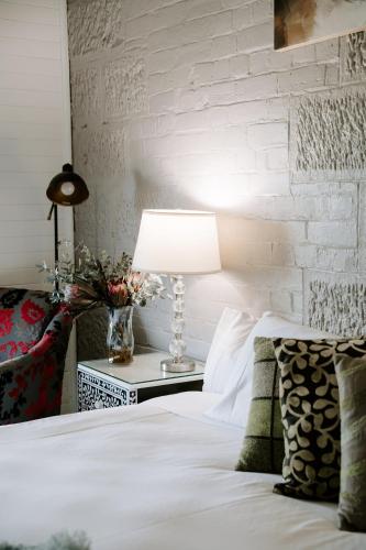 a bed with a lamp on a night stand next to a brick wall at The Abbey in Warwick