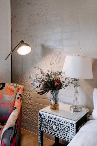 a table with a lamp and a vase with flowers on it at The Abbey in Warwick