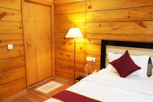 a bedroom with wooden walls and a bed and a lamp at Mountain BNB Hartola in Rāmgarh