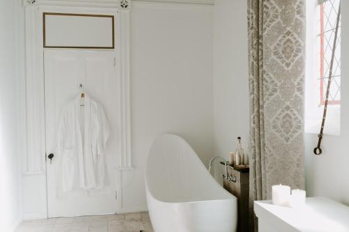 a white bathroom with a tub and a sink at The Abbey in Warwick