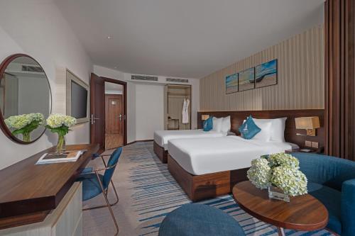 a hotel room with a bed and a couch at Canvas Danang Beach Hotel in Da Nang