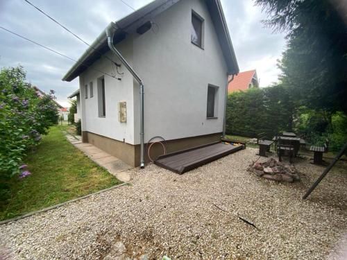 a small white house with a patio and a fire pit at FLÓRA VENDÉGHÁZ A BALATONNÁL in Lovas
