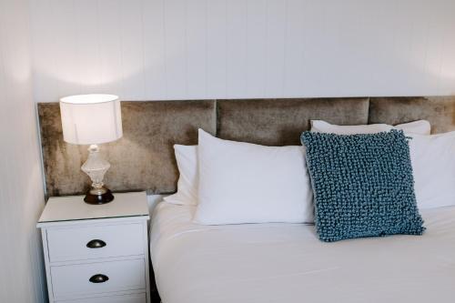 a bedroom with a white bed with a lamp on a night stand at The Abbey in Warwick