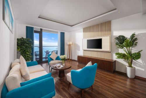 a living room with blue chairs and a television at Canvas Danang Beach Hotel in Da Nang
