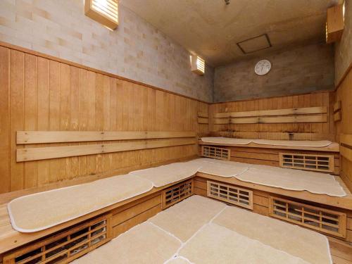a sauna with wooden walls and a clock on the wall at Nishitetsu Inn Kokura in Kitakyushu