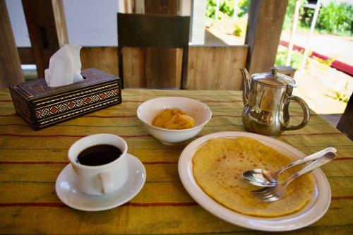 a table with a plate of food and a cup of coffee at Authentique Homestay in Rantepao