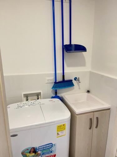 a small kitchen with a white refrigerator and blue pipes at Tamarielys 1BR Vista a la montaña in Rodadero