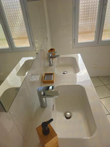- une salle de bains blanche avec deux lavabos et deux fenêtres dans l'établissement Appartement proche de la mer, à Pomérols