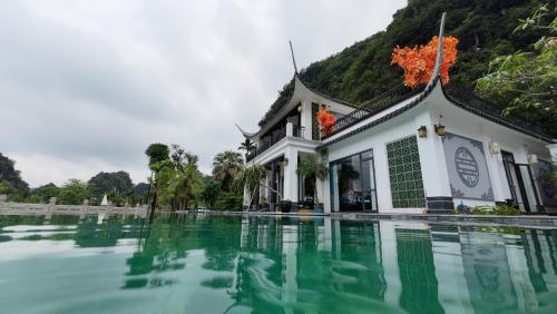 a building with a pool of water in front of it at Happy Tam Coc Ecolodge in Ninh Binh