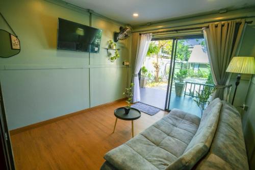 a living room with a couch and a tv at Green Garden House กรีนการ์เด้นเฮ้าส์ นครพนม in Nakhon Phanom