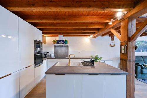 eine Küche mit weißen Schränken und einer Holzdecke in der Unterkunft La Cormorane - 100m plage - Parking in La Plaine-sur-Mer