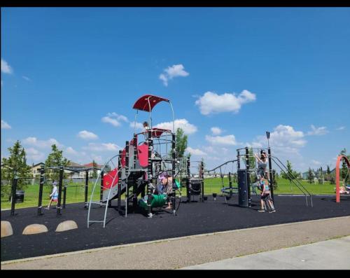 a playground in a park with children playing on it at Chic 2BR Suite with Kitchen, Laundry, Near Elk Island & West Edmonton Mall in Edmonton