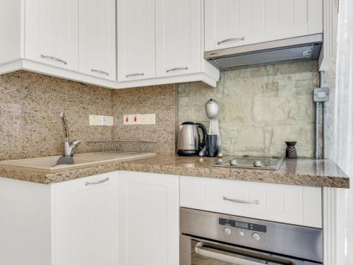 a white kitchen with white cabinets and a sink at Sanders Arsorama Arsos in Arsos