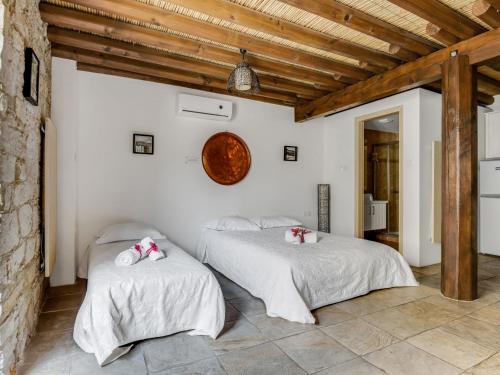 two beds in a room with white walls and wooden ceilings at Sanders Arsorama Arsos in Arsos