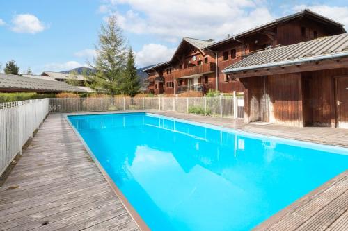 une piscine avec une terrasse en bois à côté d'une maison dans l'établissement Cabana & Alp'évasion - Pools, Sauna, Pool Table, à Samoëns