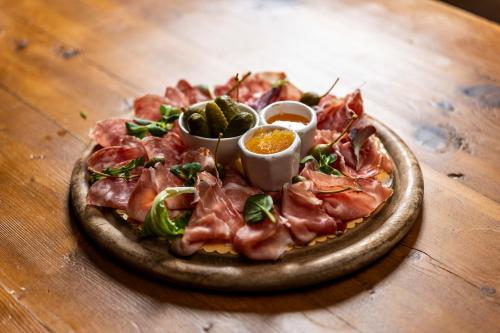 a pizza on a plate on a wooden table at Gaarten Hotel Benessere Spa by Kleos Group Collection in Gallio
