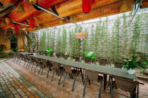 a long table and chairs in a room with plants at Ali Garden Homestay Tràng An Ninh Bình in Xuân Sơn