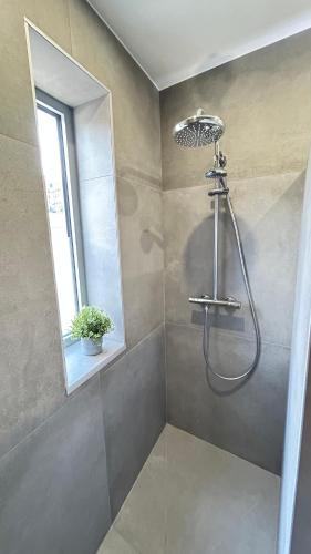 une douche avec pommeau de douche dans une salle de bain dans l'établissement 2 chambres dans appartement neuf, terrasse sud, meublé contemporain, parking, à Aix-les-Bains