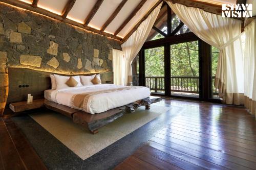a bedroom with a bed with a stone wall at StayVista at The Forest Echoes with Pool, BBQ in Wayanad