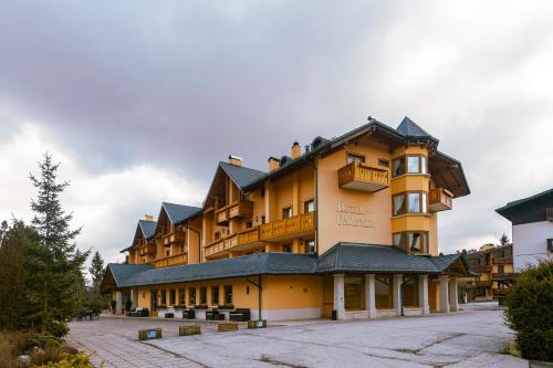 a large yellow building with a balcony on top of it at Gaarten Hotel Benessere Spa by Kleos Group Collection in Gallio