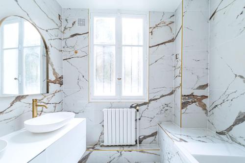 une salle de bain blanche avec un lavabo et un miroir dans l'établissement Appartement raffiné - Arc de Triomphe, à Paris