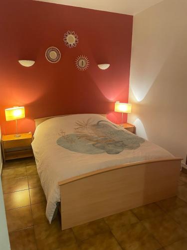 - une chambre avec un lit aux murs rouges et 2 lampes dans l'établissement Joli appartement avec terrasse Baccara, à Gréoux-les-Bains