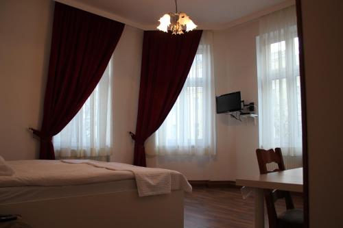 1 dormitorio con cortinas rojas, 1 cama y escritorio en Arnes Hotel Vienna en Viena