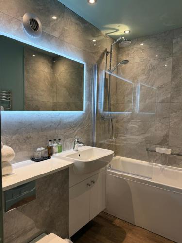 a bathroom with a sink and a shower and a tub at The George Hotel Easingwold in Easingwold