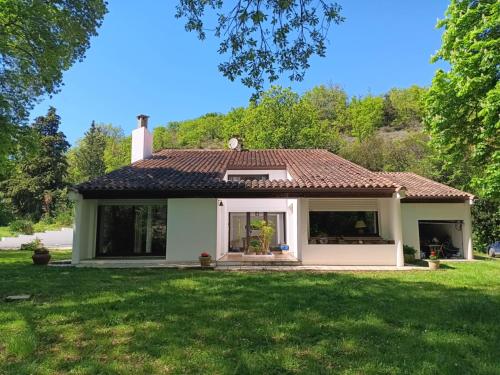 a small white house with a green yard at Maison de campagne avec lac privé in Fendeille