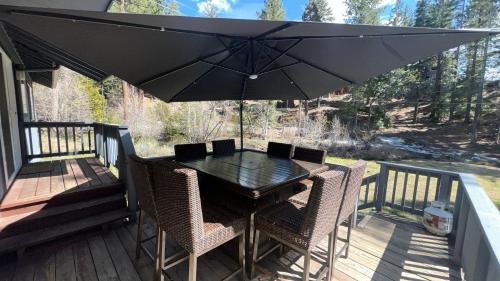 a black table with chairs and an umbrella on a deck at Creek Side Summit home in Stateline