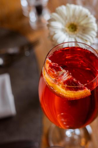 a drink with an orange slice in a glass at Gaarten Hotel Benessere Spa by Kleos Group Collection in Gallio